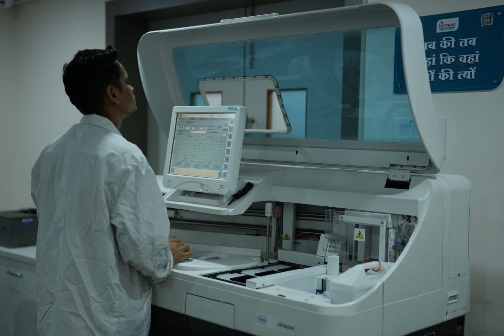 A lab technician operates a clinical analyzer in a modern laboratory setting.