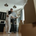Happy couple dancing together in their new home filled with moving boxes, celebrating new beginnings.