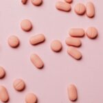 Flat lay photo of pink pills on a pastel pink background, ideal for pharmaceutical themes.