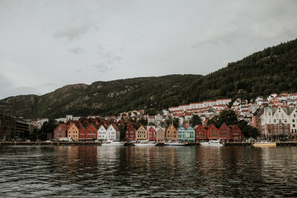 Colorful Bryggen buildings along the waterfront in Bergen, Norway, with mountain backdrop.