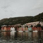 Colorful Bryggen buildings along the waterfront in Bergen, Norway, with mountain backdrop.
