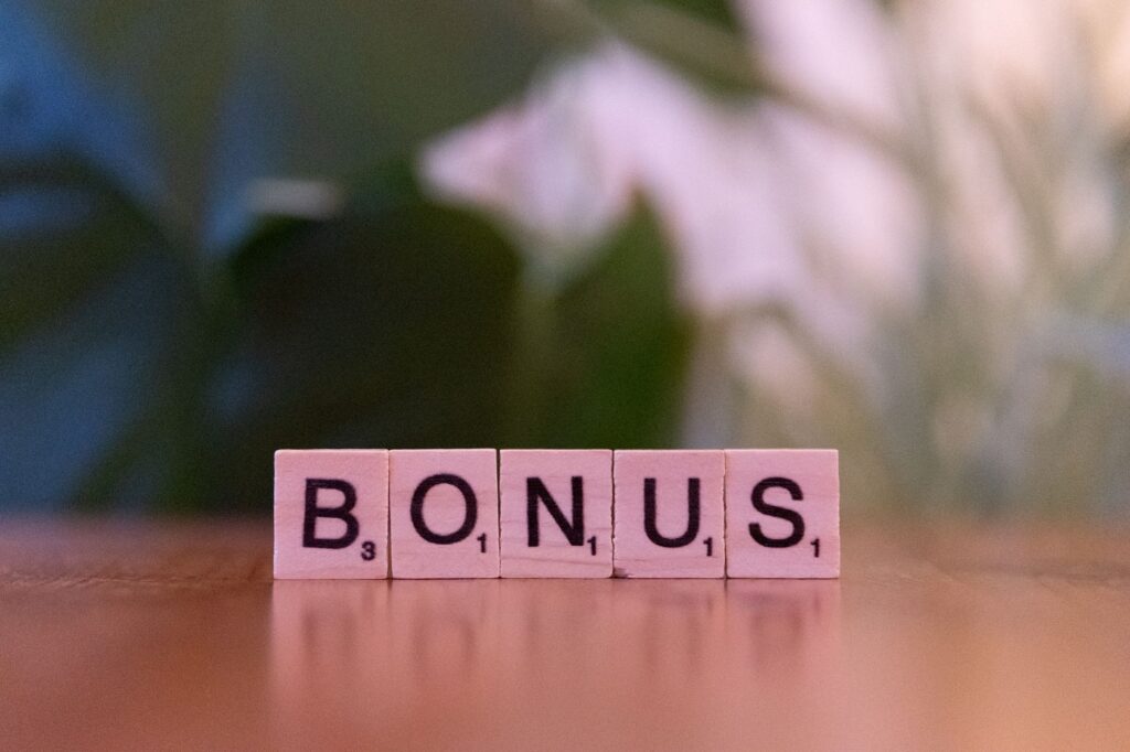 Close-up of the word BONUS spelled with Scrabble tiles on a table.
