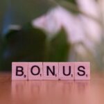 Close-up of the word BONUS spelled with Scrabble tiles on a table.