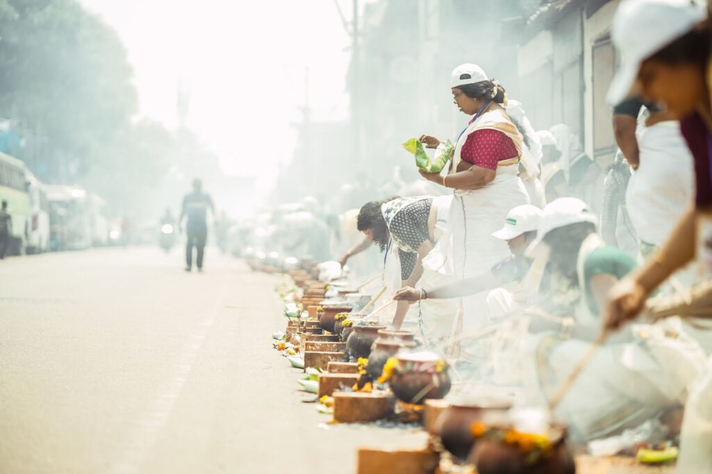Women in traditional attire participate in outdoor cooking festival.