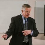 A business professional leading a presentation in a modern conference room.