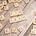Fintech spelled out with wooden letter tiles on a rustic wooden background.