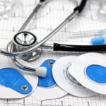 Close-up of medical tools including electrodes and stethoscope on ECG printout.