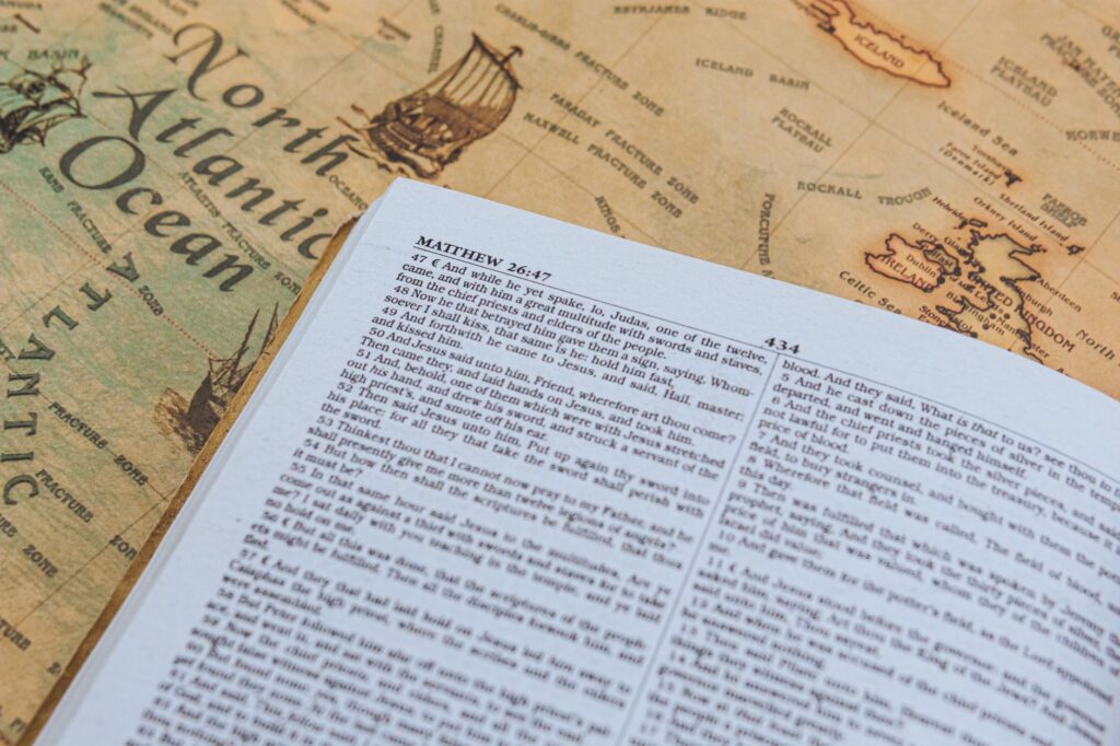 Open Bible with text from Matthew 26:47 on vintage map of North Atlantic Ocean.