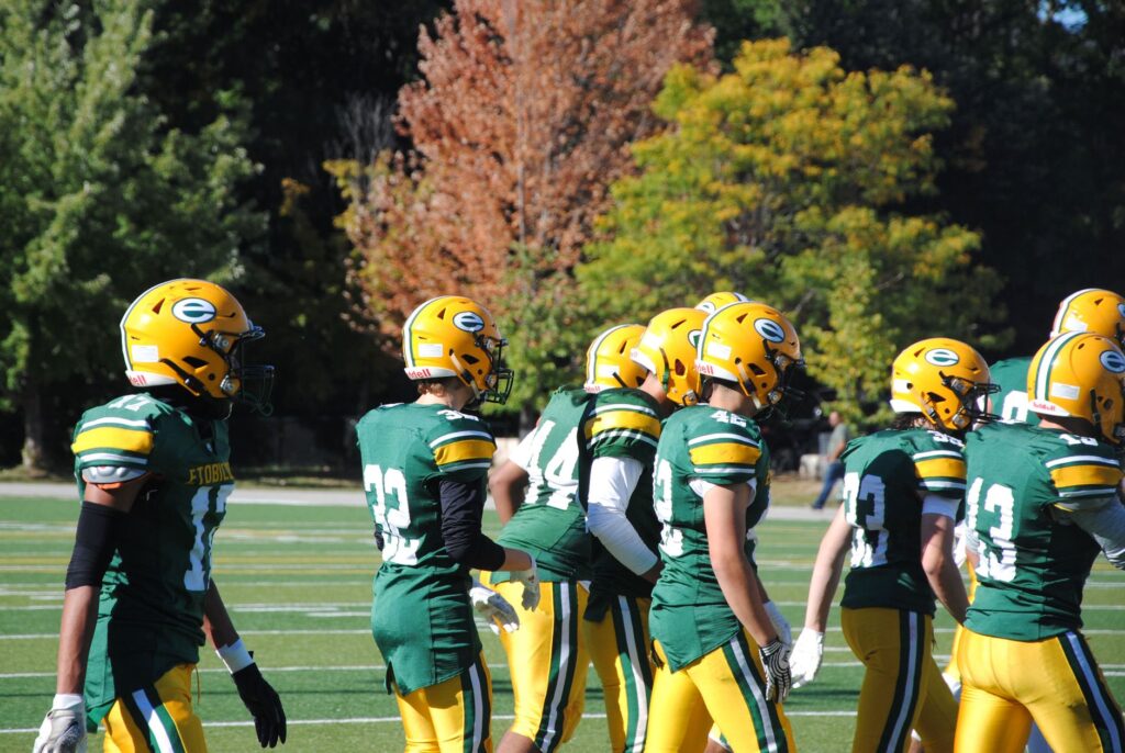 A team of American football players in green uniforms on a sunny day.