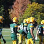 A team of American football players in green uniforms on a sunny day.