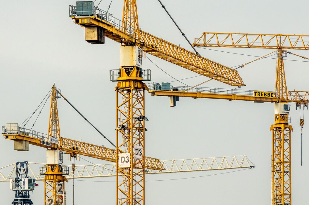 Cluster of yellow tower cranes at a construction site with a gloomy sky background.
