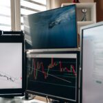 A home office setup featuring multiple monitors displaying trading charts and data analysis.