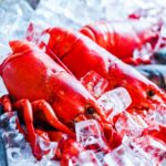 Vibrant red lobsters chilling on a bed of ice, perfect for seafood lovers.