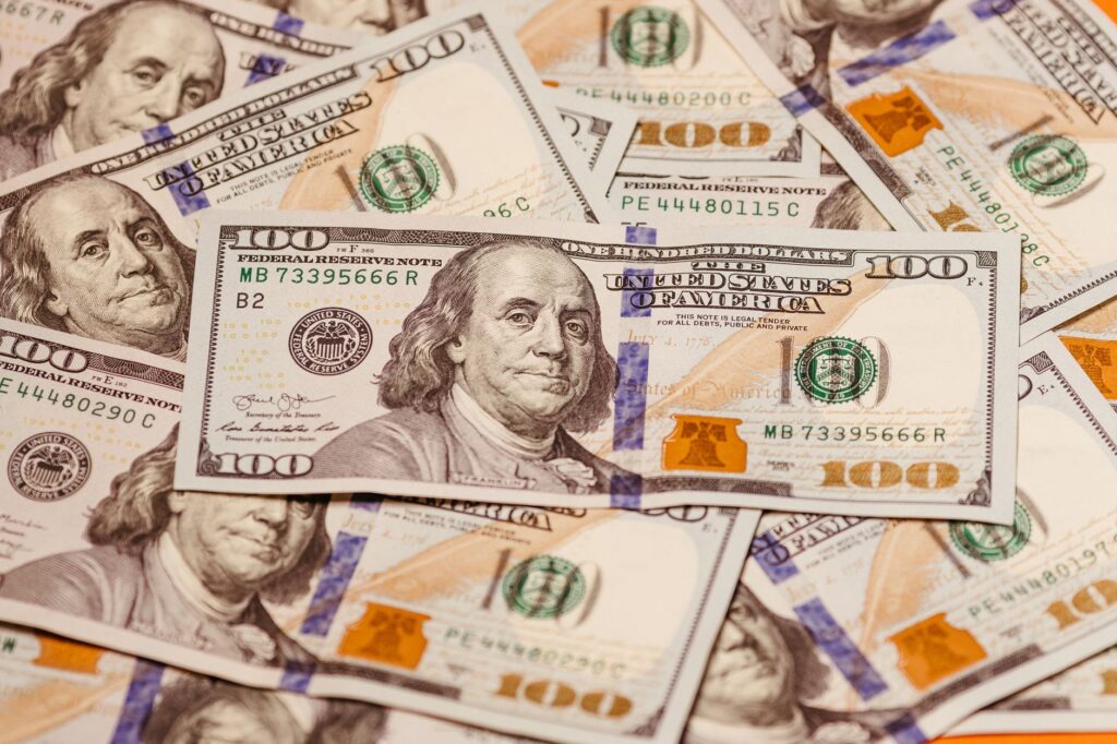 Close-up of multiple US hundred dollar bills featuring Benjamin Franklin, emphasizing wealth and finance.
