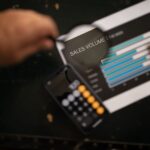 A focused examination of sales volume data using a magnifying glass and calculator.
