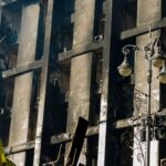 A damaged building in Kyiv, Ukraine with the Ukrainian flag displayed prominently.