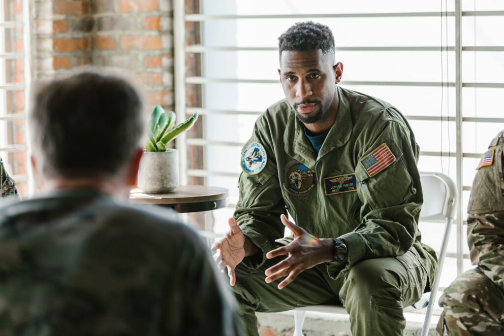 A group of military veterans participate in a supportive therapy session indoors.