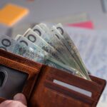 Brown leather wallet containing Polish zloty banknotes on cluttered desk