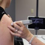 Healthcare professional conducting an ultrasound on a shoulder injury in a medical office.