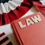 A law book with bold letters placed beside a red, white, and black decorative ribbon.