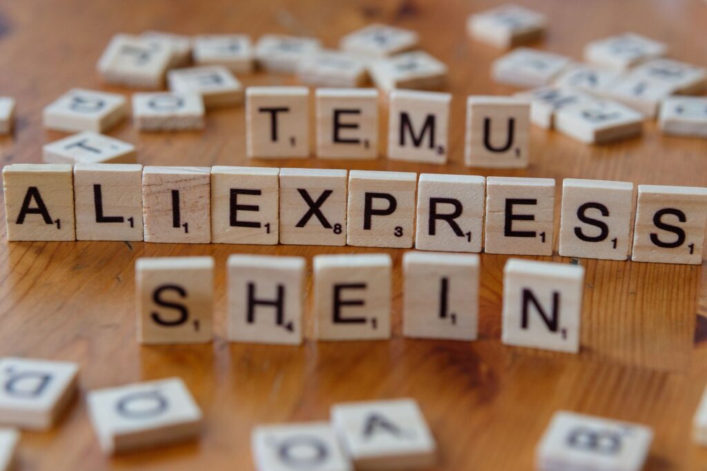Wooden Scrabble tiles display popular e-commerce platforms on a wooden surface.