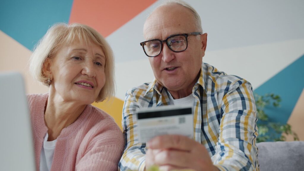 Senior couple using a credit card while shopping online at home.