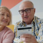 Senior couple using a credit card while shopping online at home.