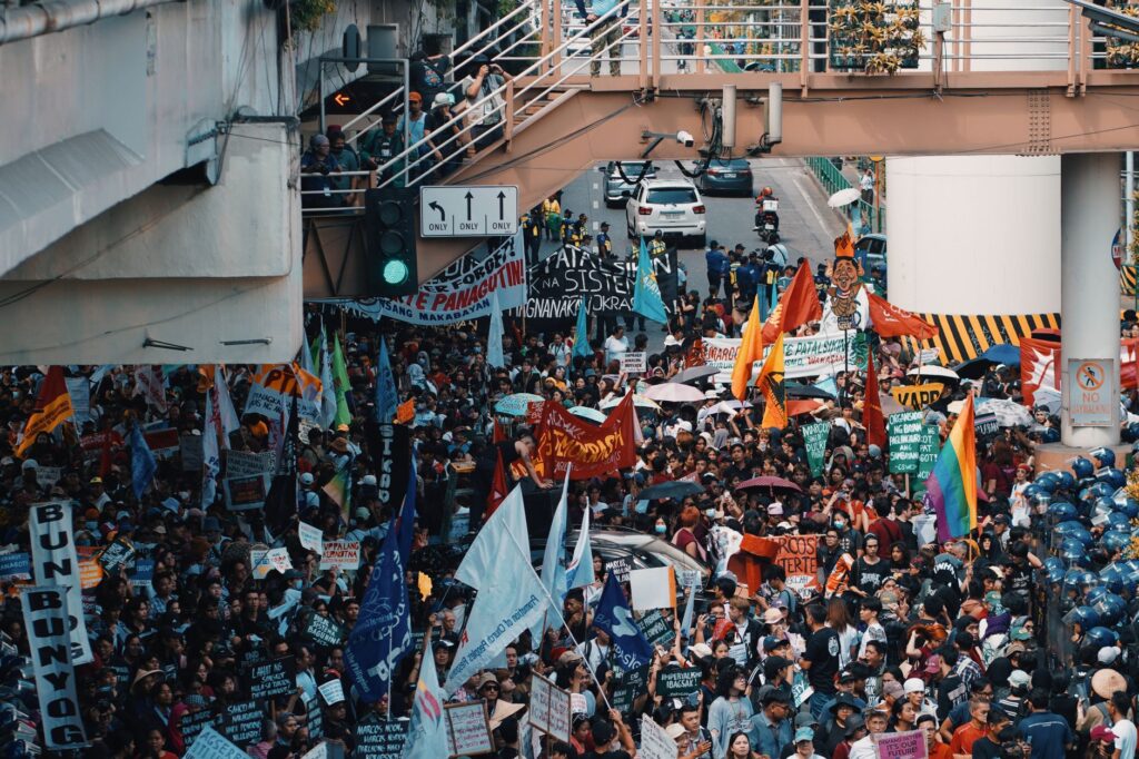 A vibrant street protest filled with diverse banners and flags.