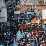 A vibrant street protest filled with diverse banners and flags.