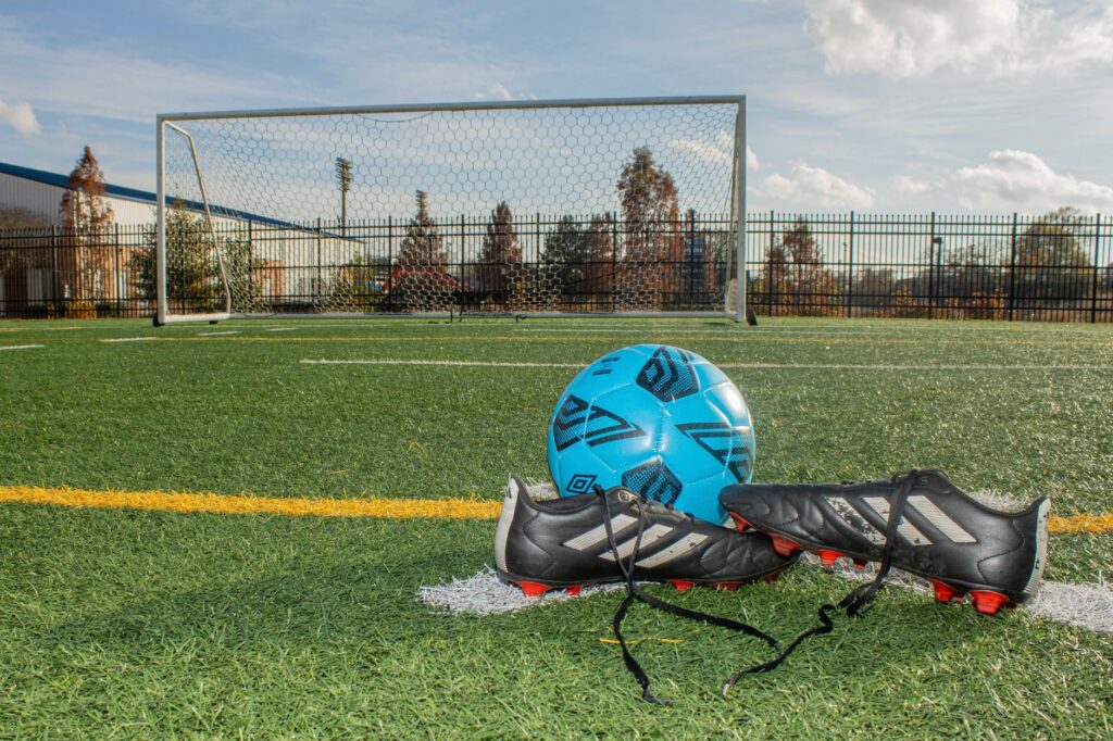 Soccer ball and cleats on a football field in Norfolk, Virginia, displaying a vibrant sports setting.