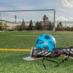 Soccer ball and cleats on a football field in Norfolk, Virginia, displaying a vibrant sports setting.