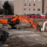 Excavators operating at an urban construction site, surrounded by residential buildings.