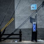 A vintage payphone beside a concrete wall in Los Angeles with striking shadows.