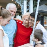 A joyful multigenerational family gathering, embracing each other outdoors with happiness.