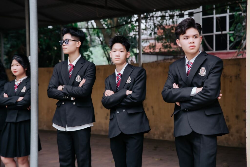 Group of teenagers standing confidently in school uniforms outdoors, showcasing unity and style.