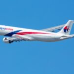 Malaysia Airlines Airbus A330 in flight with clear blue sky backdrop.