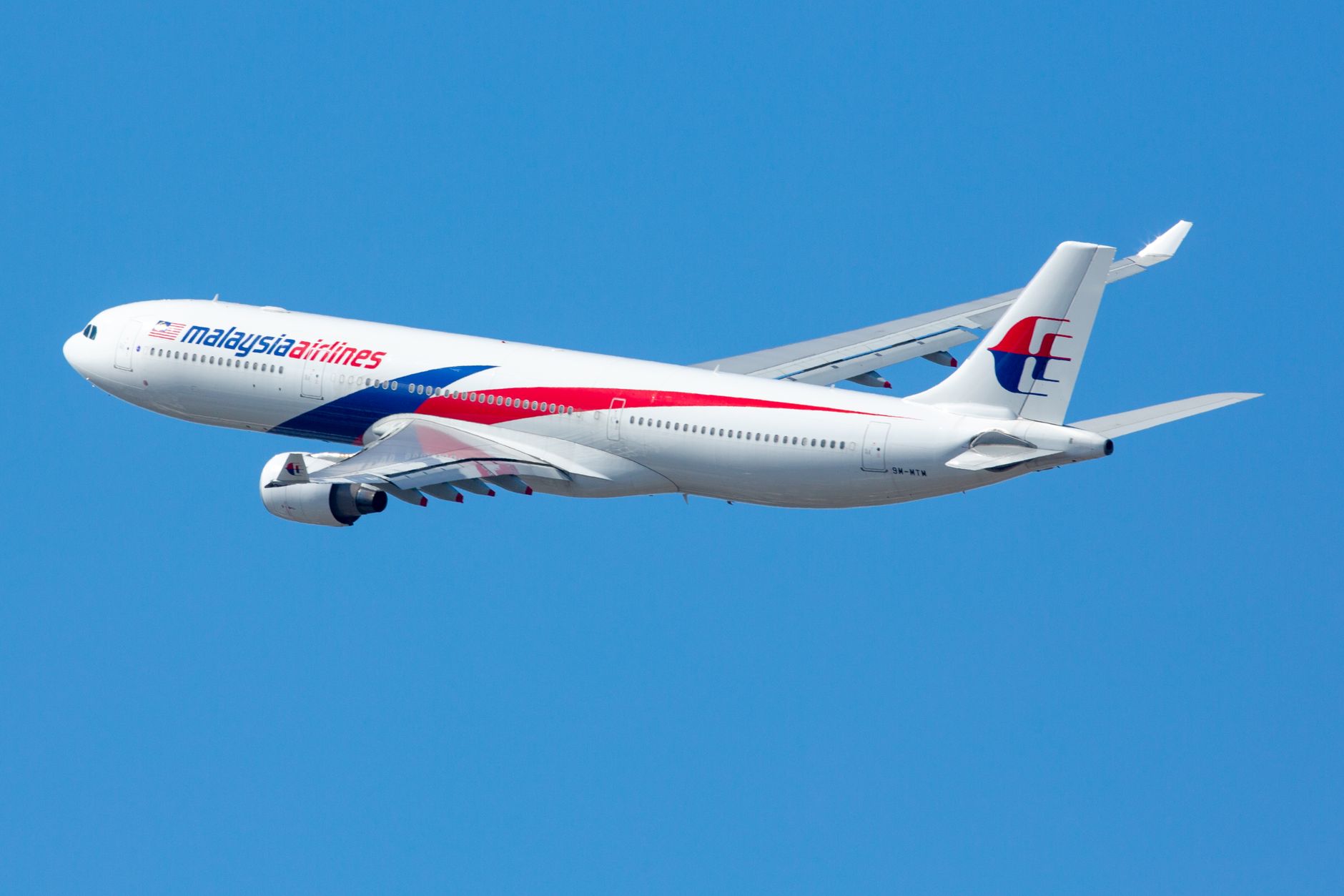 Malaysia Airlines Airbus A330 in flight with clear blue sky backdrop.