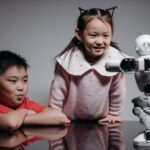 Two children interacting with a small robot, showcasing innovation and technology in a playful setting.
