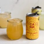 Vibrant display of cannabis-infused drinks in cans and glasses, featuring Blood Orange Cardamom flavor.