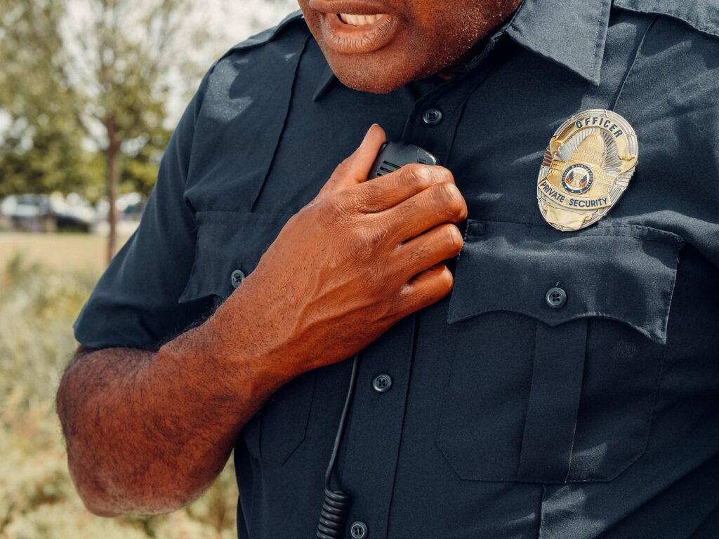 Close-up of a security officer using a radio outdoors, showcasing professional security attire.