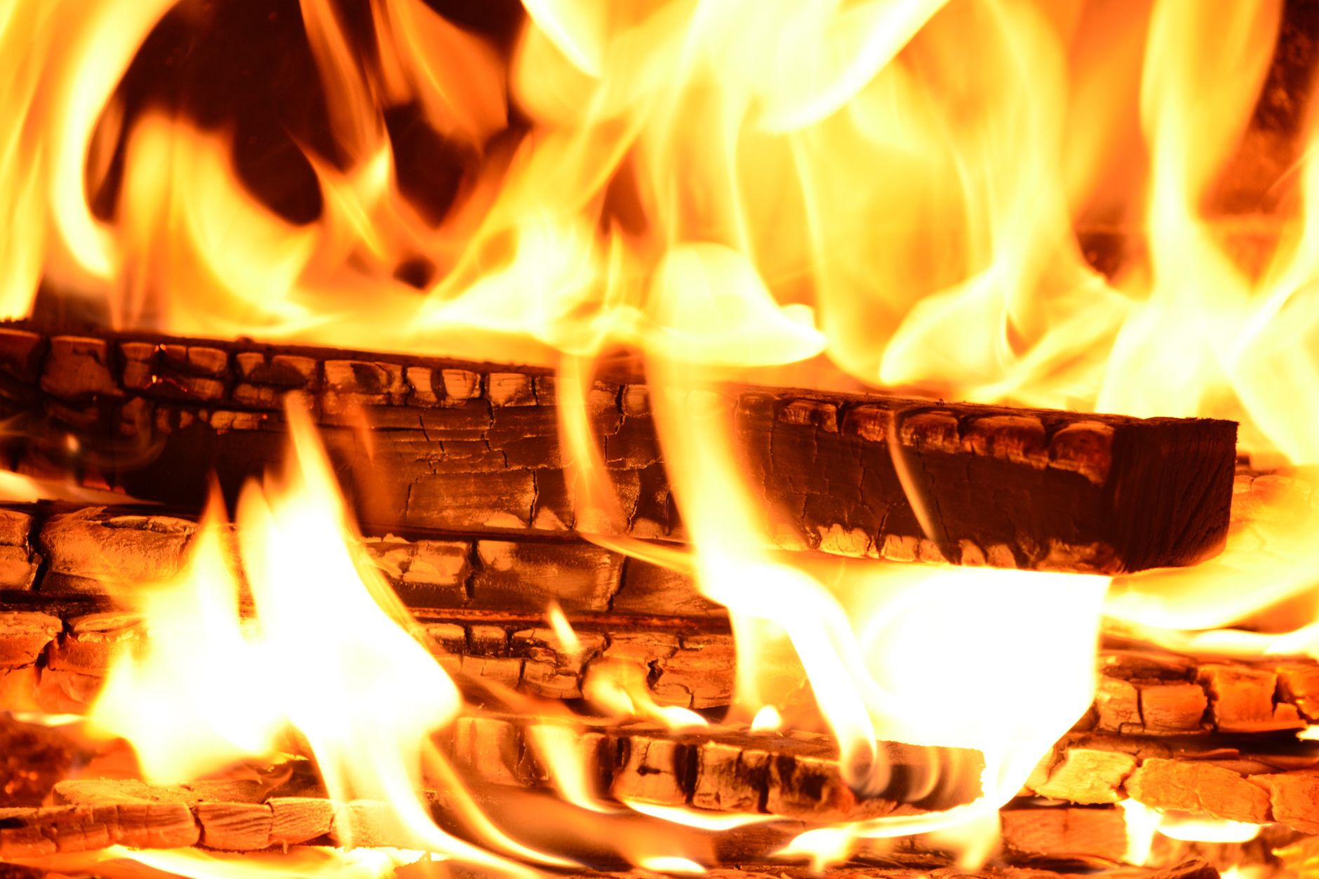 Captivating close-up of a log burning with vivid yellow and orange flames. Ideal for fire-themed visuals.