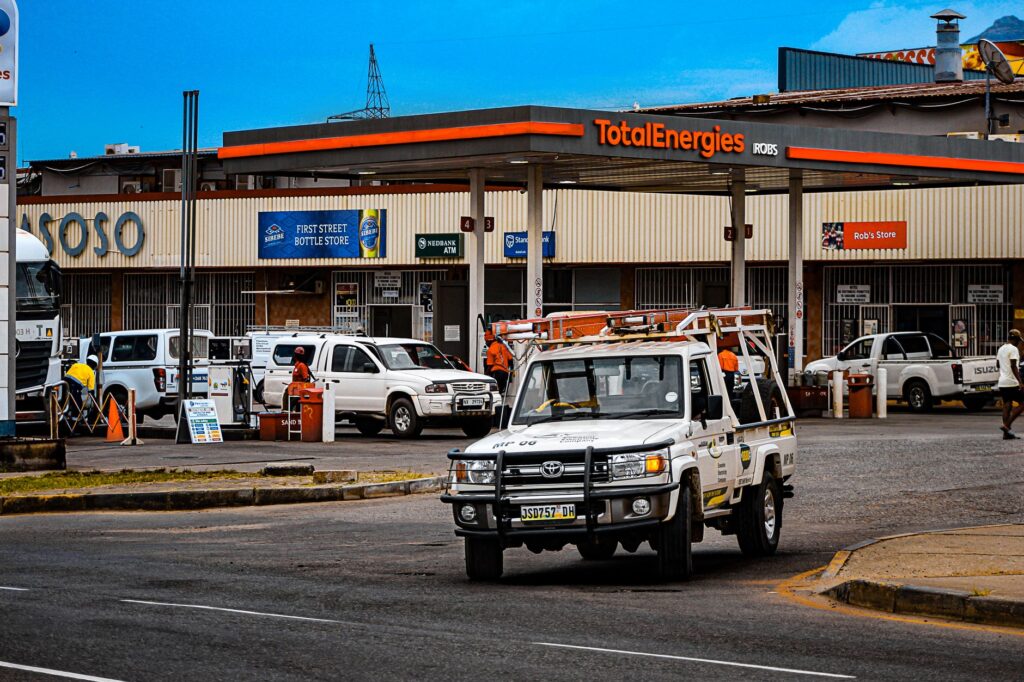 Busy street scene near a TotalEnergies gas station in Matsapha, Eswatini, with vehicles and shops.