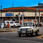 Busy street scene near a TotalEnergies gas station in Matsapha, Eswatini, with vehicles and shops.