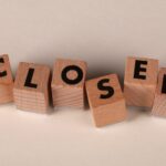 Wooden blocks spell 'closed' on a beige background, symbolizing closure or shut down.