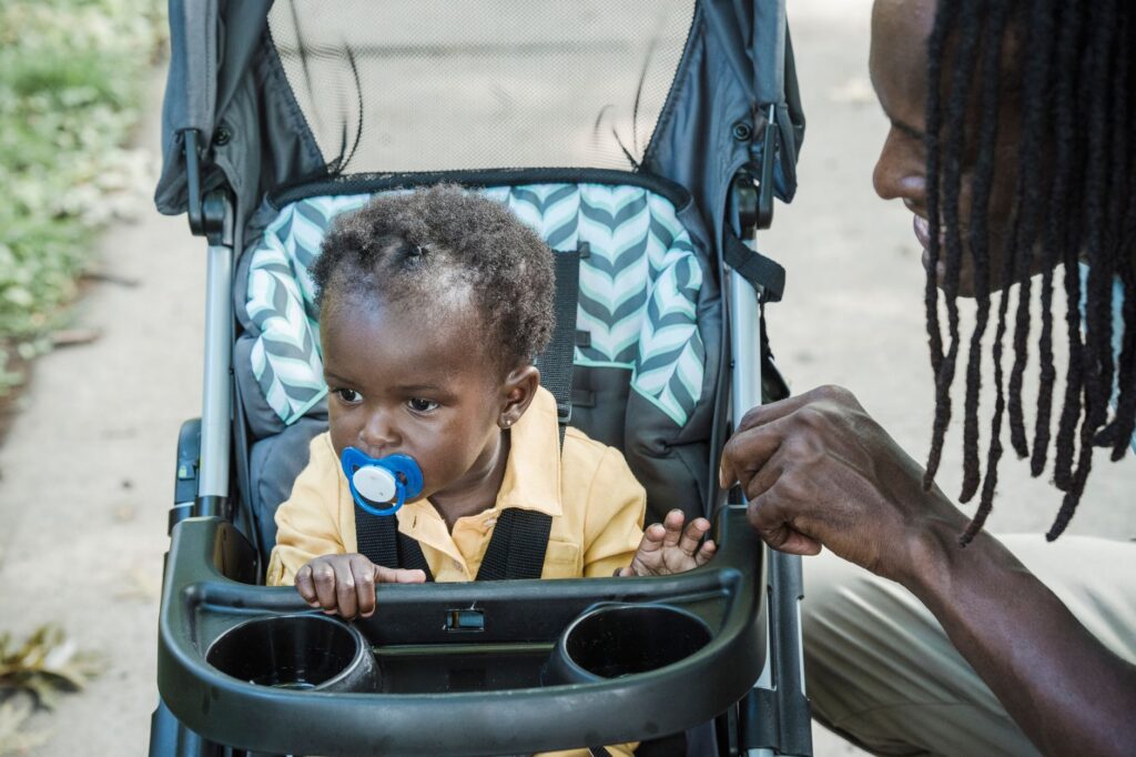 Father interacts with baby in stroller outdoors; a moment of bonding and care.
