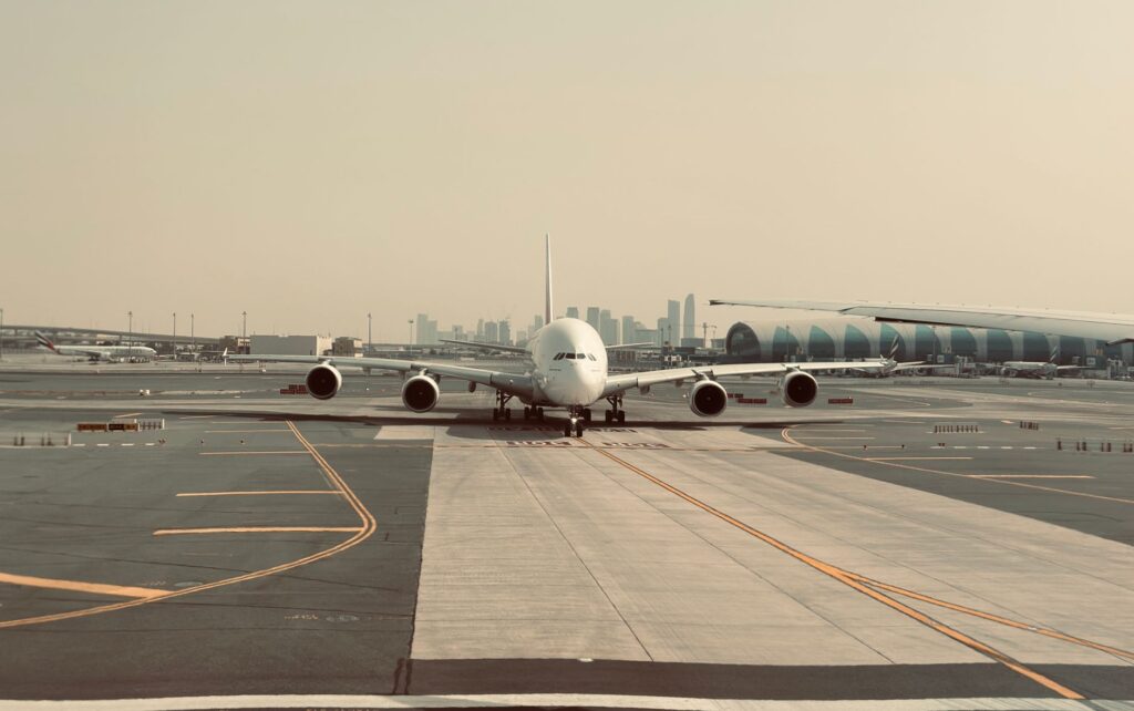 A large airplane on the tarmac at Dubai International Airport with city skyline in the background.