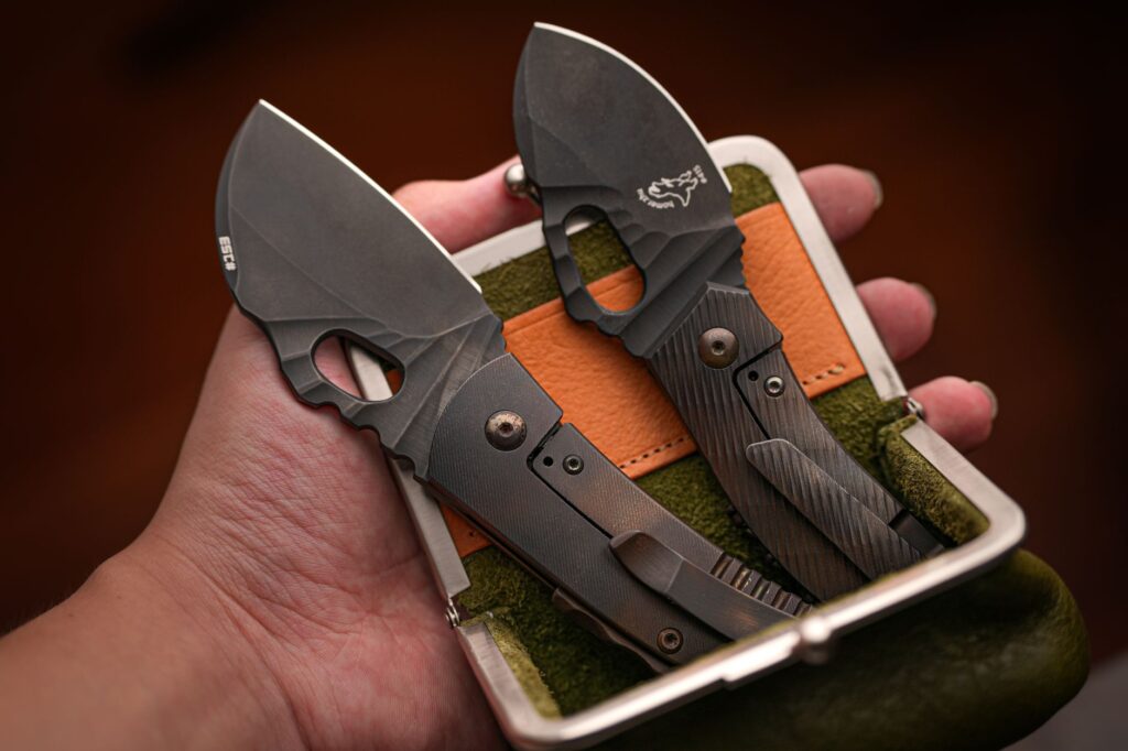 Close-up of compact folding knives in a hand-held carrying case, showcasing modern design.