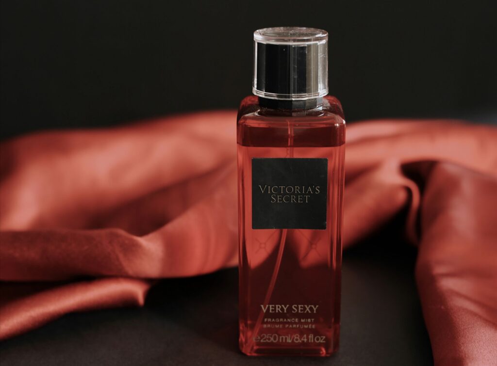 Stylish close-up of a Victoria's Secret perfume bottle with a red backdrop, exuding luxury.