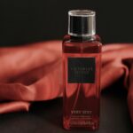 Stylish close-up of a Victoria's Secret perfume bottle with a red backdrop, exuding luxury.