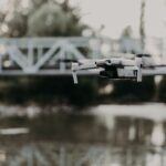 A modern drone captures stunning aerial views over a tranquil river and steel bridge.